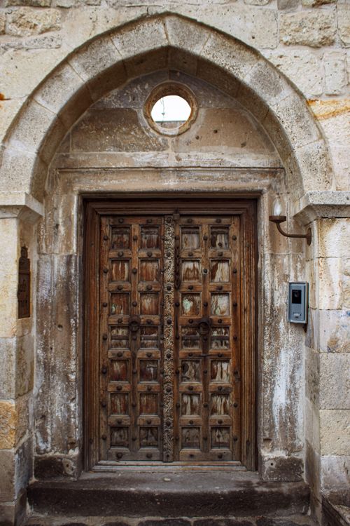 Free Historic weathered wooden door set in a stone archway, showcasing medieval architecture. Stock Photo