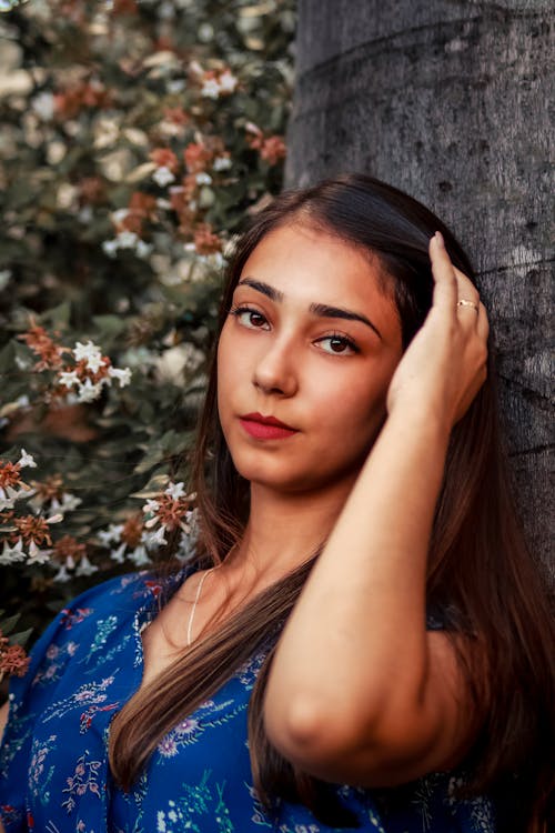 Photo of Woman Leaning on a Tree Trunk