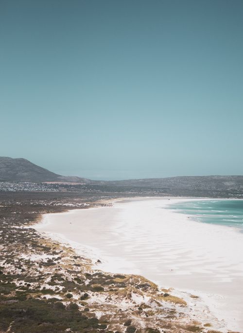 Free From above drone view of wide sandy shore of ocean with line of mountains on horizon Stock Photo
