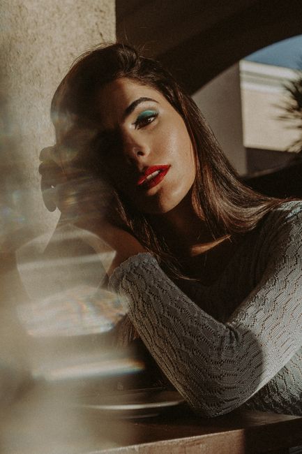 Portrait of a woman with long hair in sunlight, creating moody reflections.