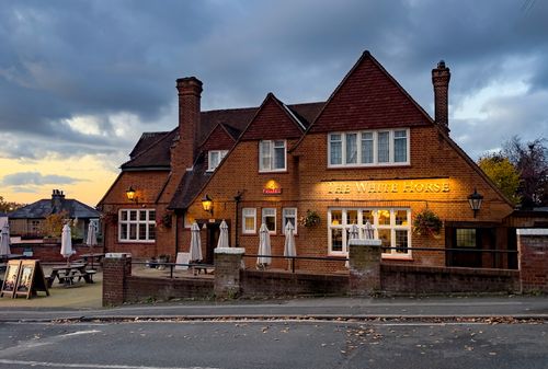Free The White Horse pub featuring classic brick design and evening ambiance under a cloudy sky. Stock Photo