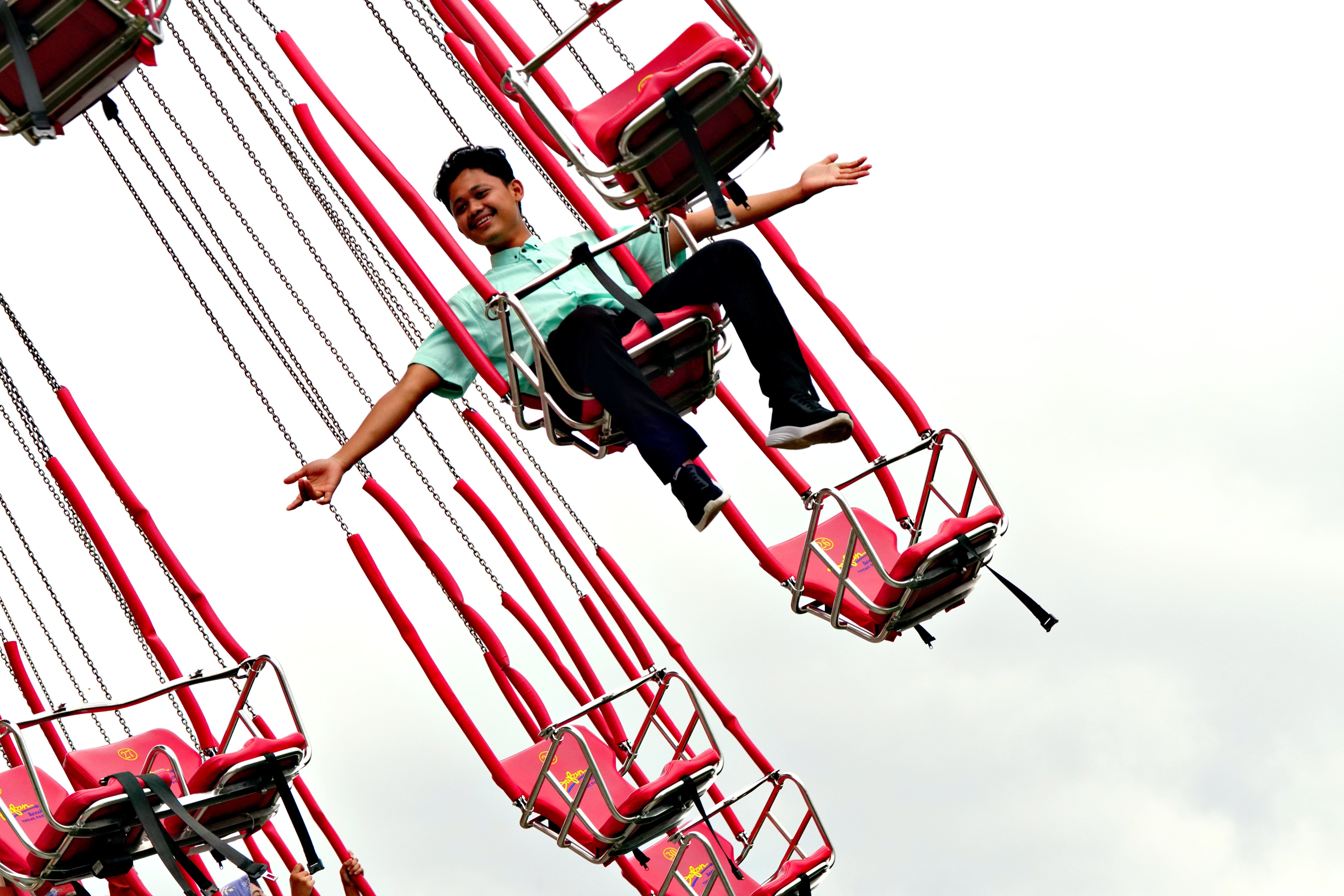 A joyful man on a swing ride at an amusement park experiencing thrill and fun outdoors.