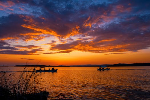 Gorgeous sunset over a peaceful lake in Bursa, Türkiye with boats silhouetted against vibrant skies