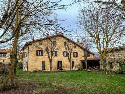 Free Charming stone farmhouse surrounded by trees in a rural landscape, serene and inviting. Stock Photo