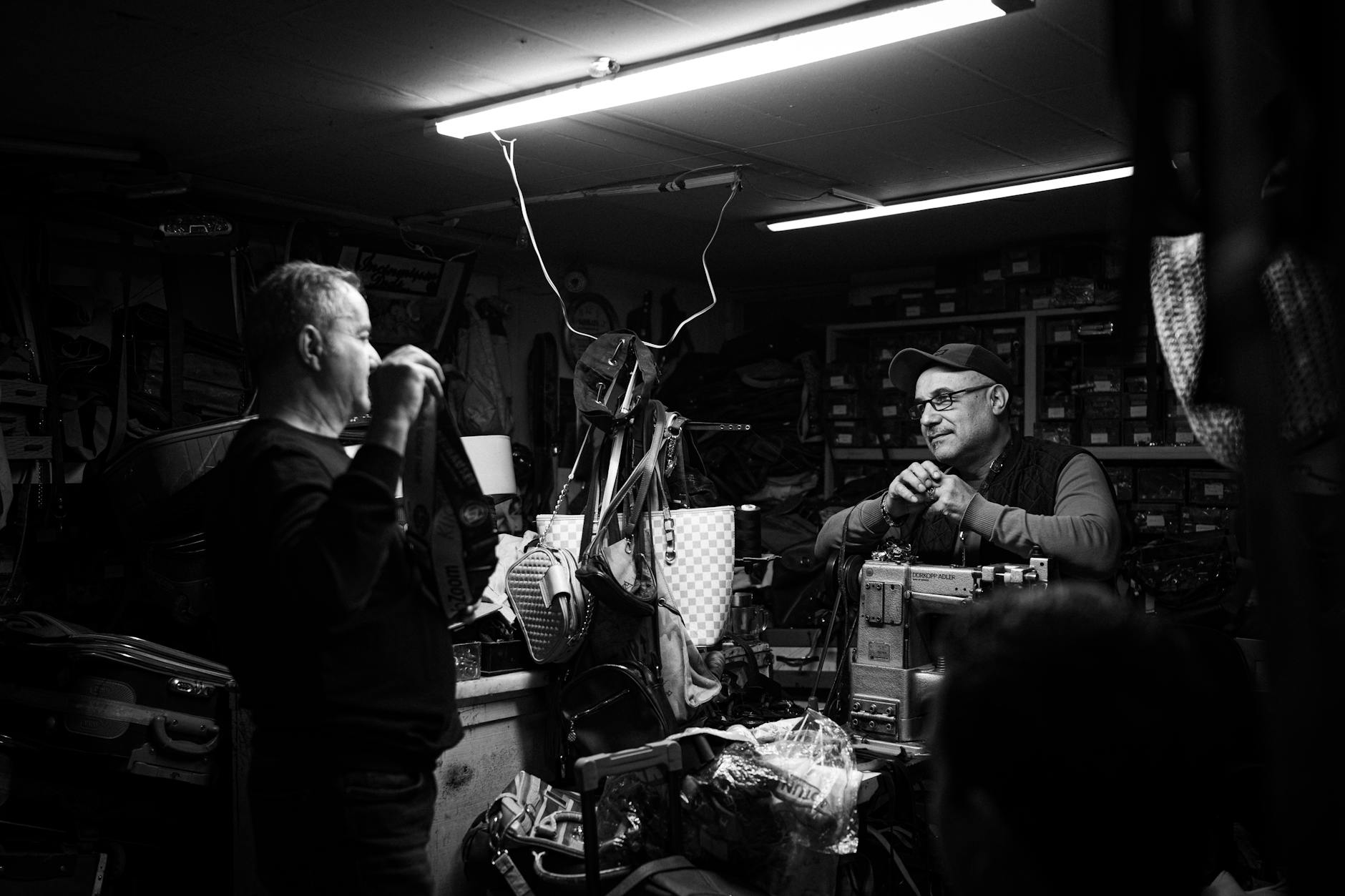 Two craftsmen engaged in conversation in a vintage workshop, showcasing tools and equipment.