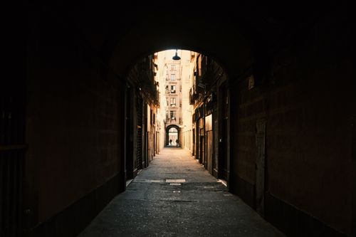 Free Explore the moody atmosphere of a narrow archway leading into a Barcelona alley, capturing a sense of mystery and urban architecture. Stock Photo