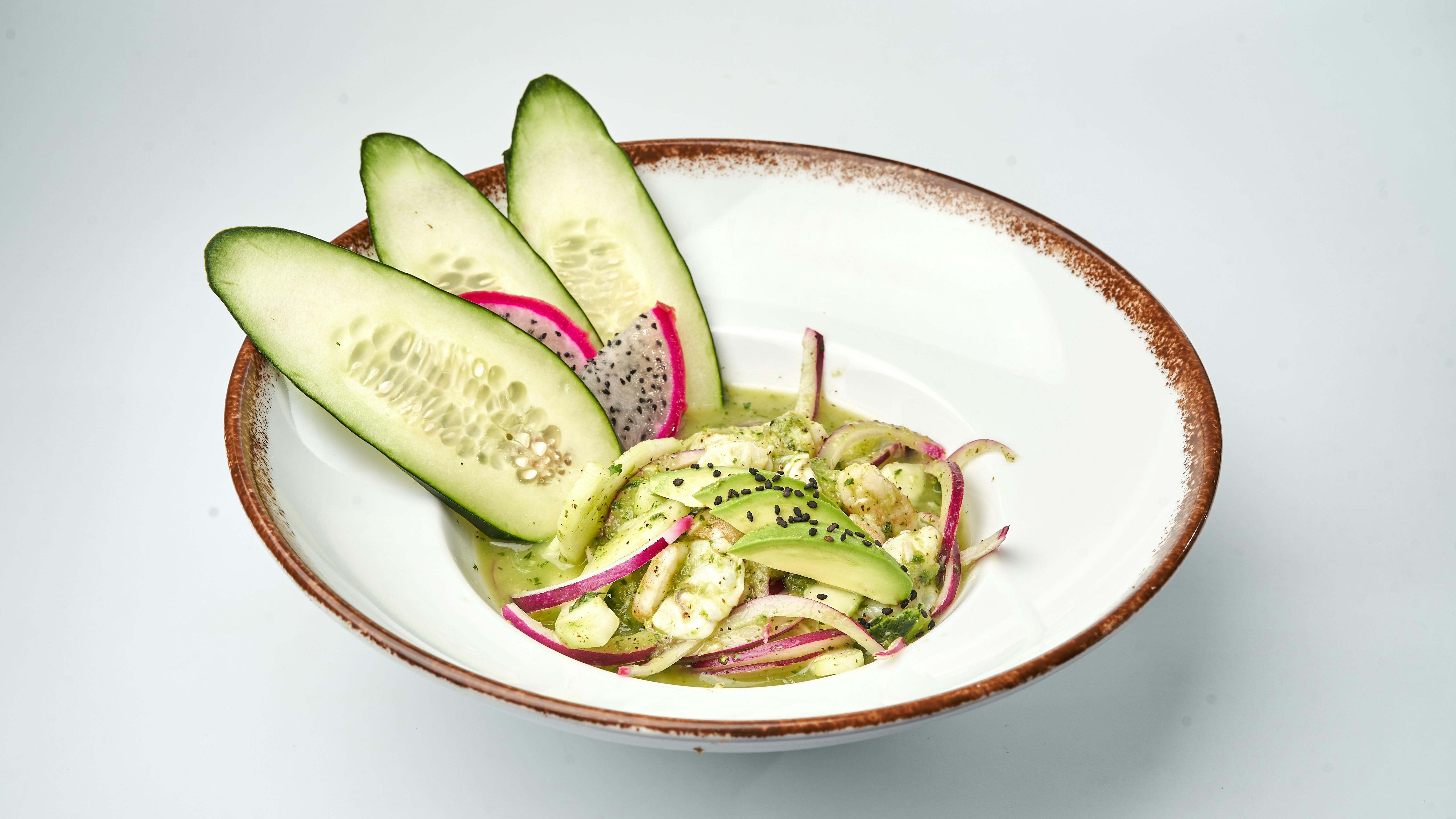 A vibrant cucumber and radish salad with herbs in a rustic bowl for a healthy meal.