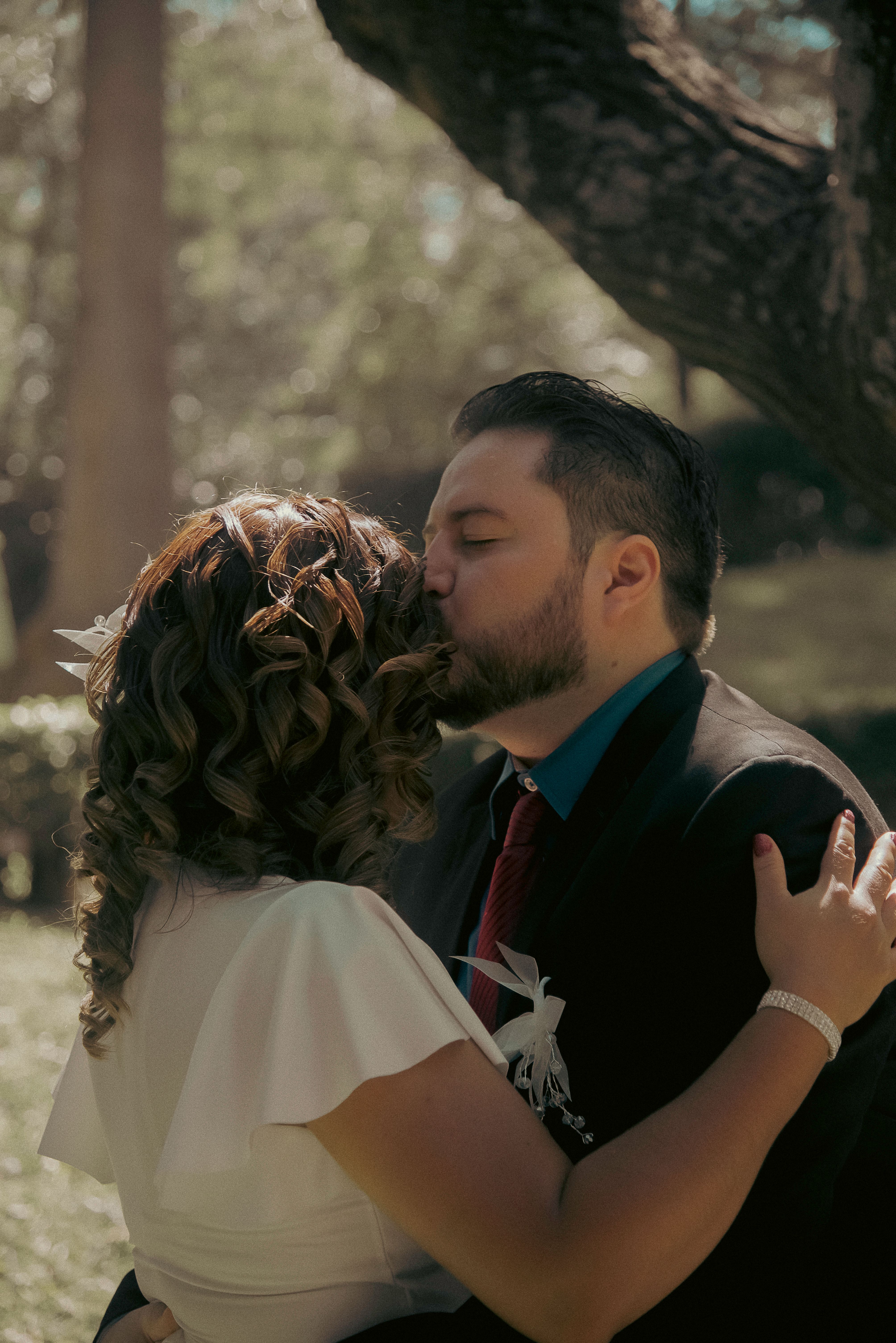 Romantic Wedding Couple Sharing a Kiss Outdoors · Free Stock Photo