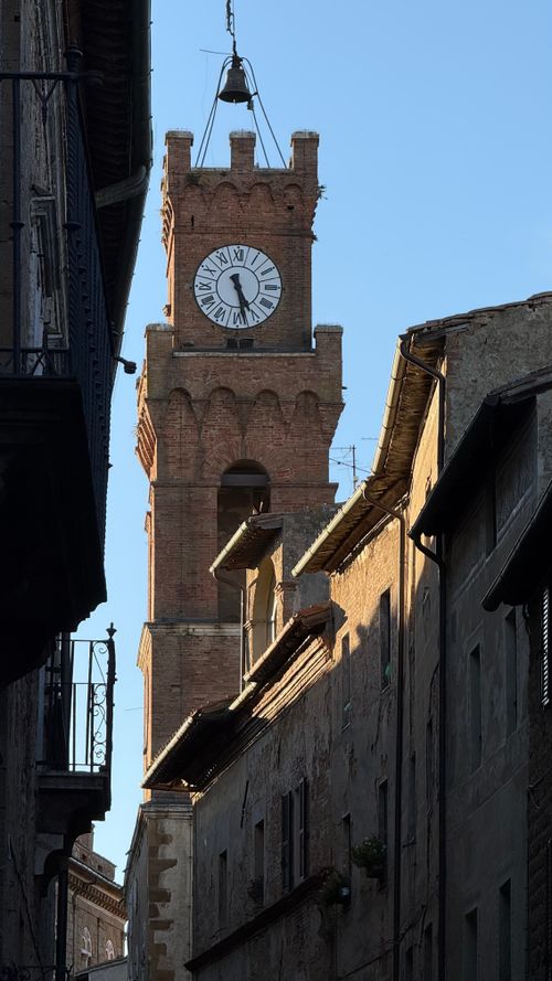 Free A beautiful brick clock tower rising between buildings during sunset. Stock Photo