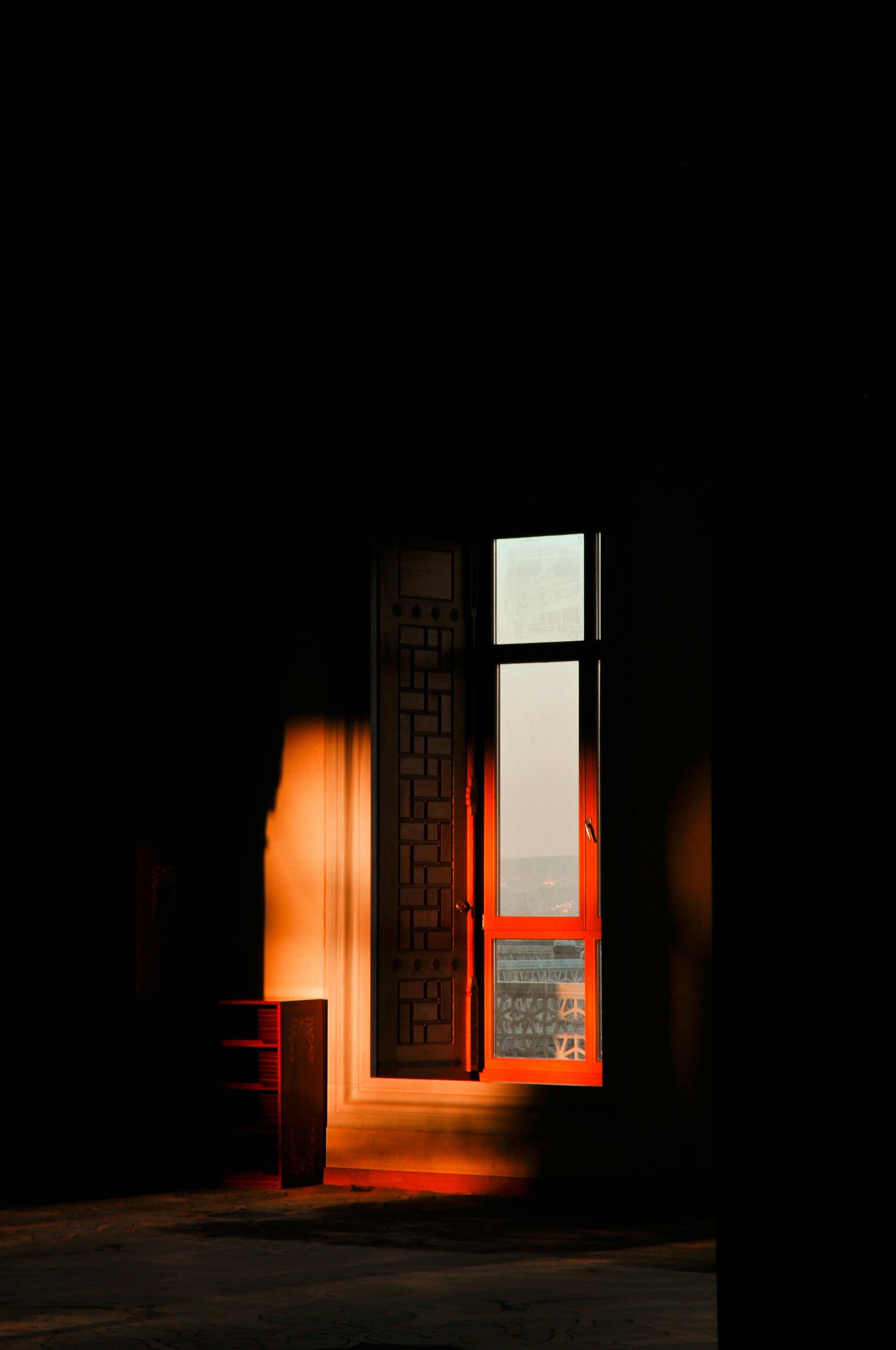 Warm sunlight casts dramatic shadows through an ornate window, creating a serene indoor atmosphere.