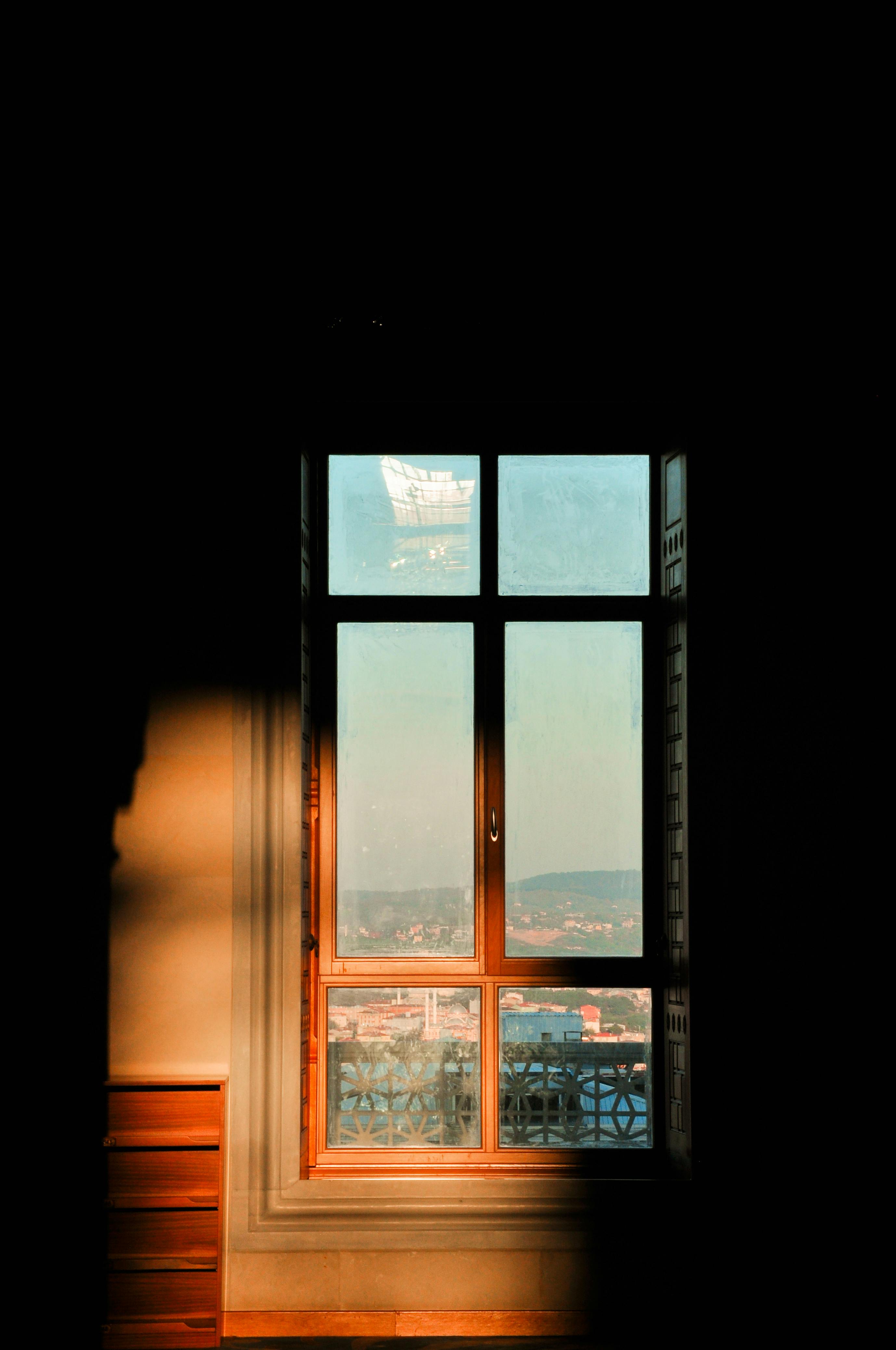 Warm-toned window view of cityscape at dusk, casting a serene, contemplative ambiance.