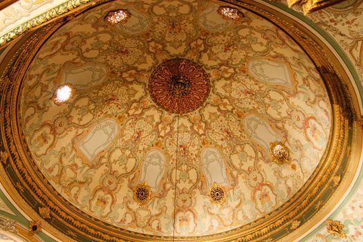 An ornate domed ceiling showcasing intricate patterns and warm gold tones in a historic building.