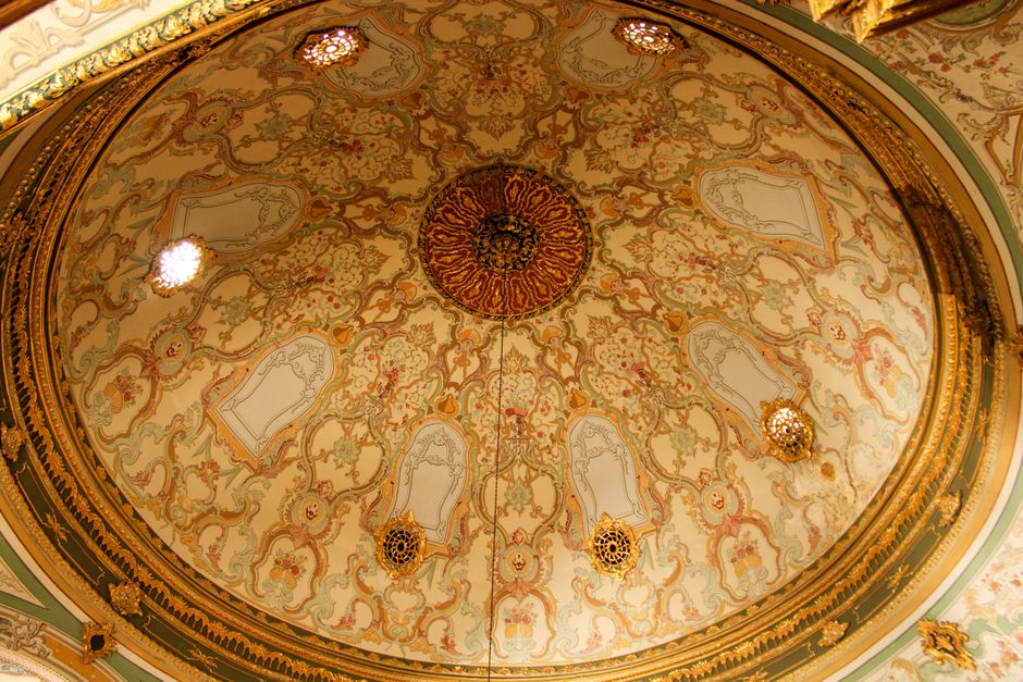 An ornate domed ceiling showcasing intricate patterns and warm gold tones in a historic building.