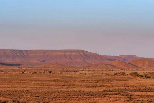 Free Expansive desert with distant mountains under clear sky, showcasing natural beauty. Stock Photo