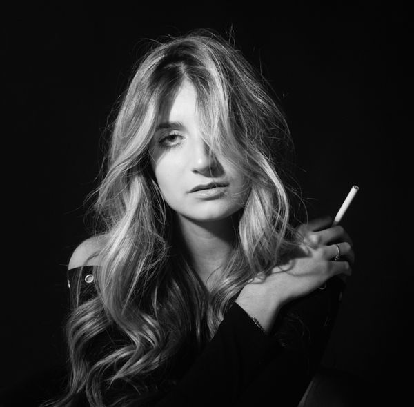 A Grayscale Photo of a Woman Smoking Cigarette while Sitting on the ...
