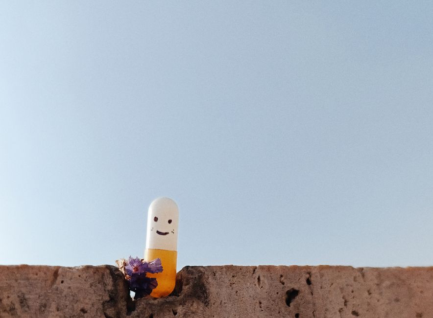 A smiling capsule set on a rustic wall with a blue sky backdrop conveying a cheerful vibe.