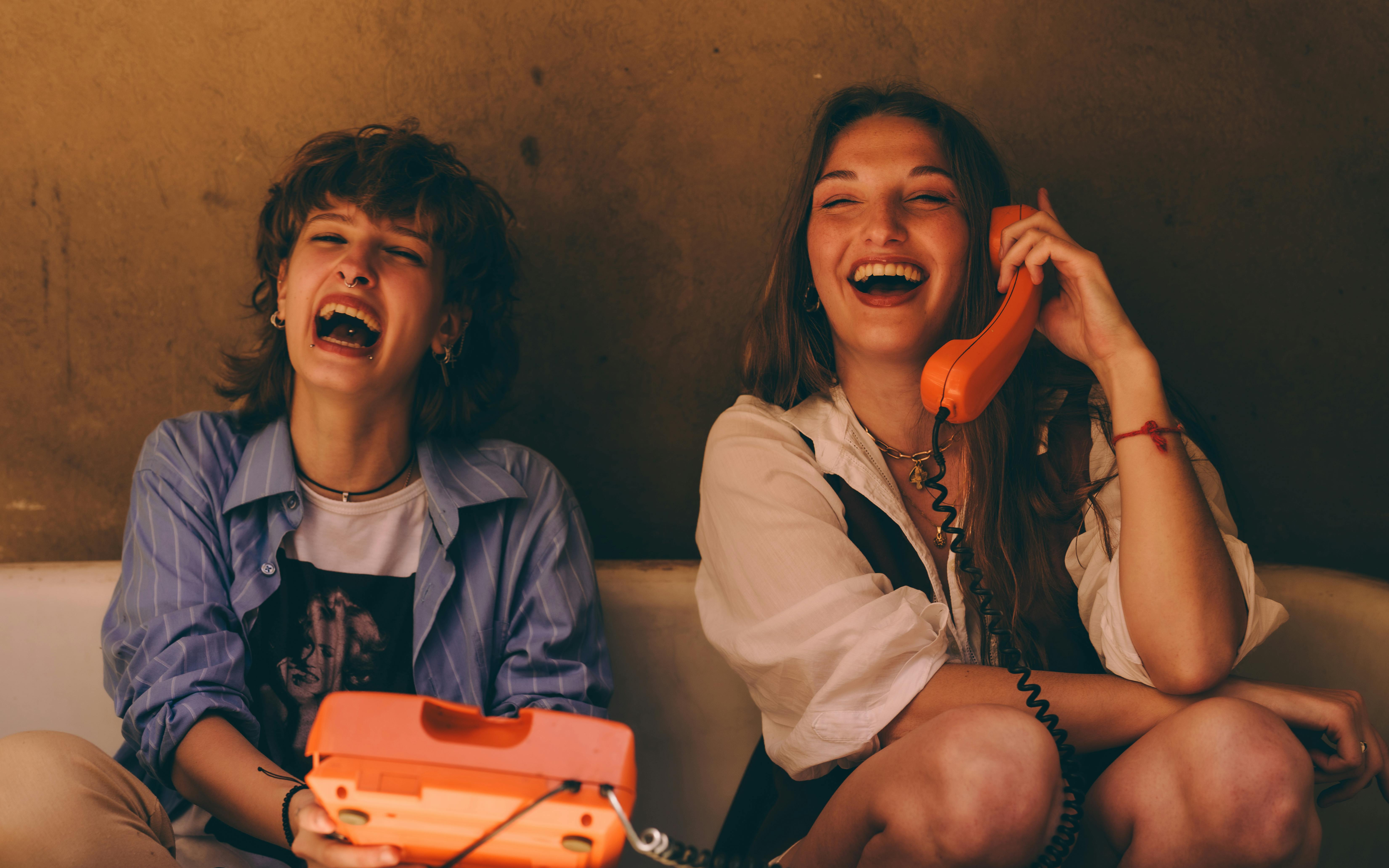 Gratis To kvinner koser seg med en latter på vintage-telefoner, og foreviger et åpenhjertig og gledelig øyeblikk. Arkivbilde