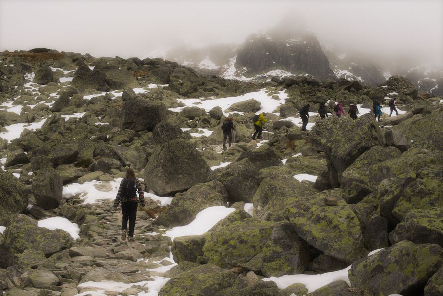 Turisté v kamenitém terénu Tater pod vrcholovým hřebenem