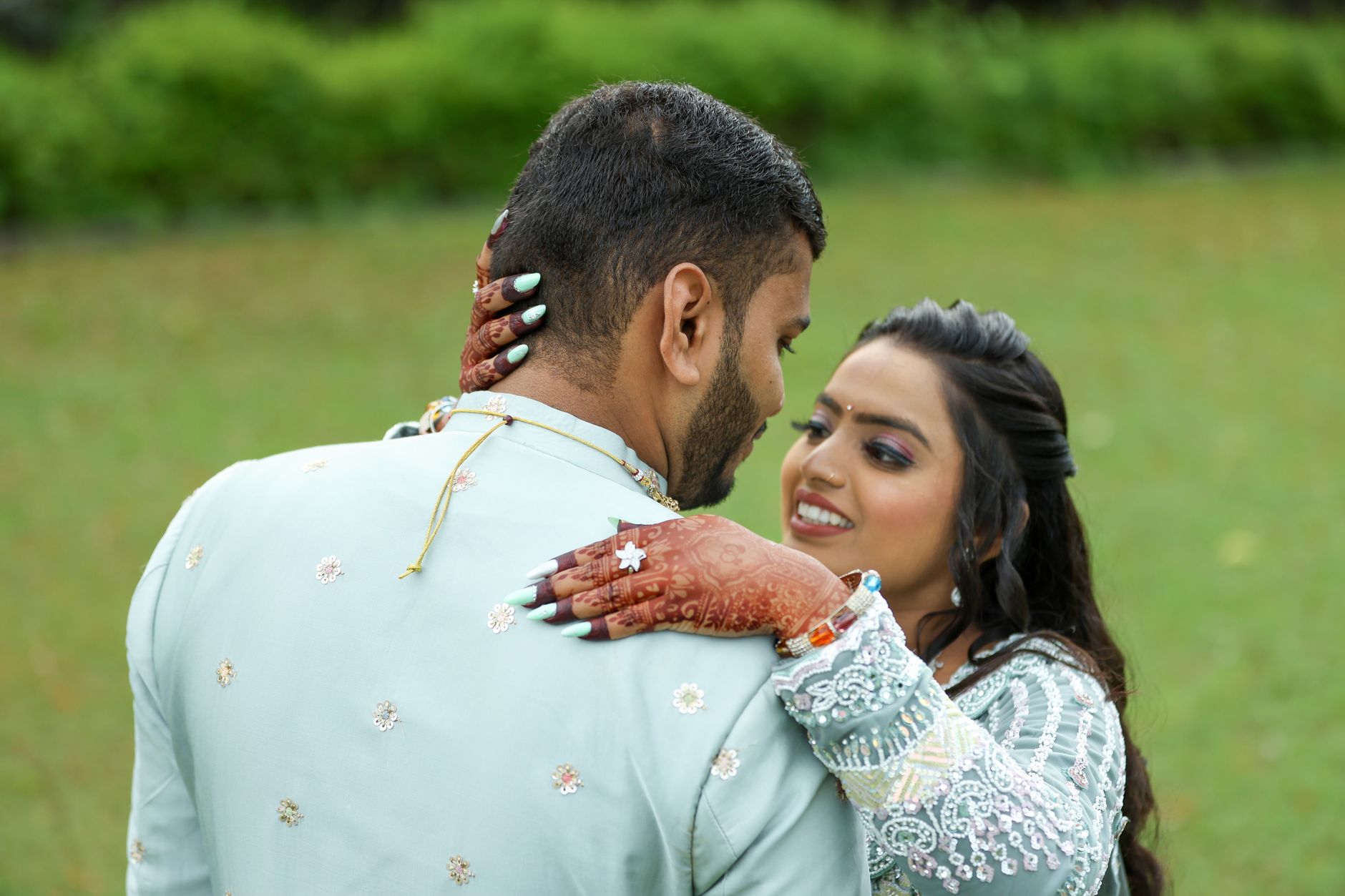 Romantic outdoor wedding moment with couple embracing, highlighting cultural details.