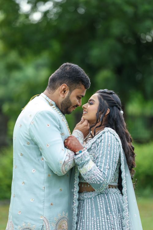 Free A loving couple in traditional attire embracing in a lush green outdoor setting, portraying a romantic moment. Stock Photo