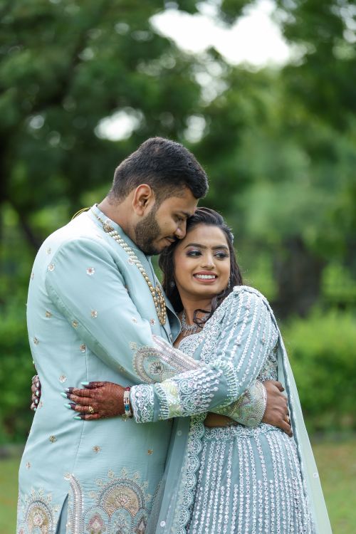 Free A happy couple in traditional attire embrace outdoors, surrounded by greenery. Stock Photo