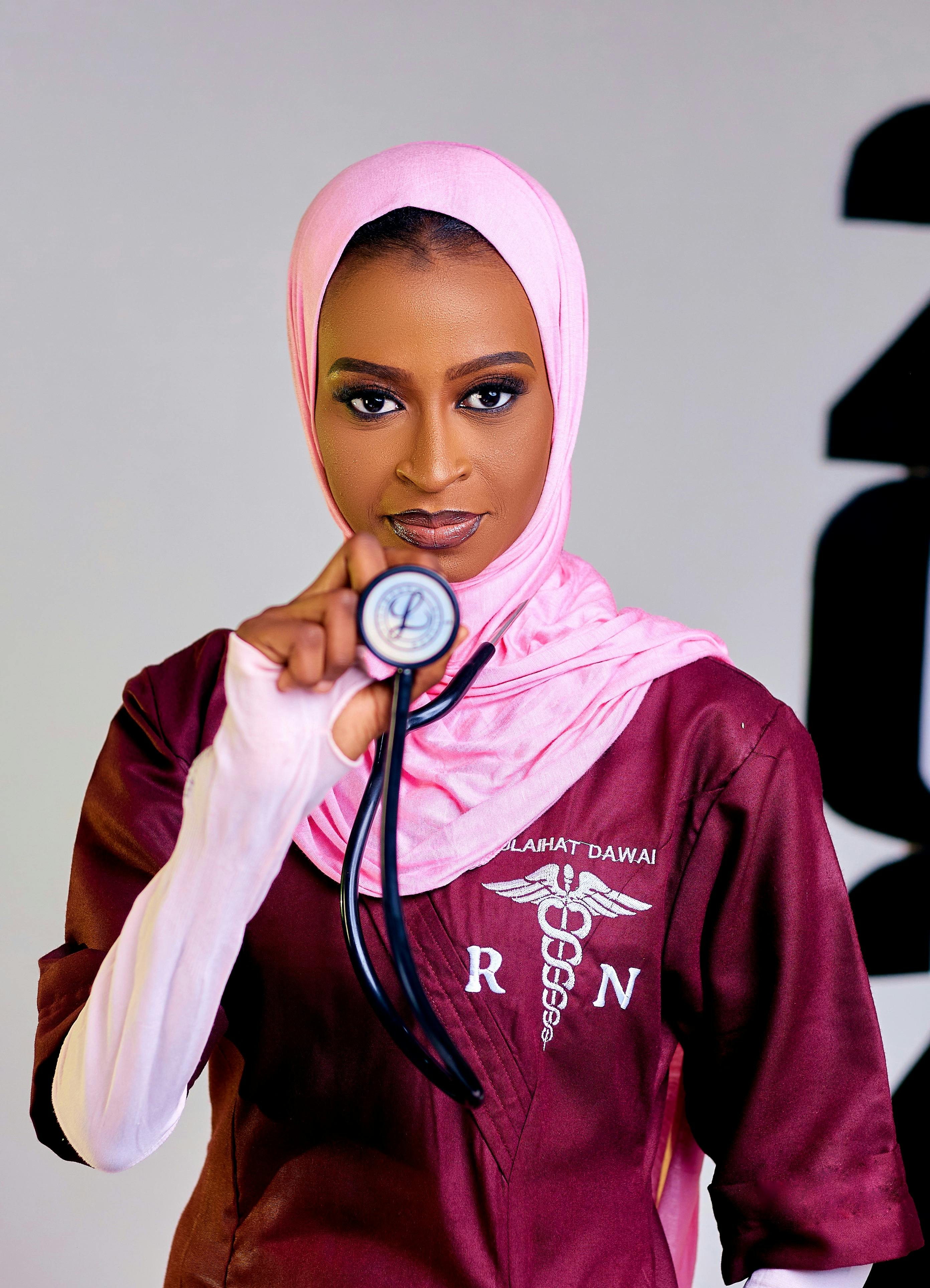 Focused female nurse in hijab holding a stethoscope, wearing professional attire. Healthcare representation.