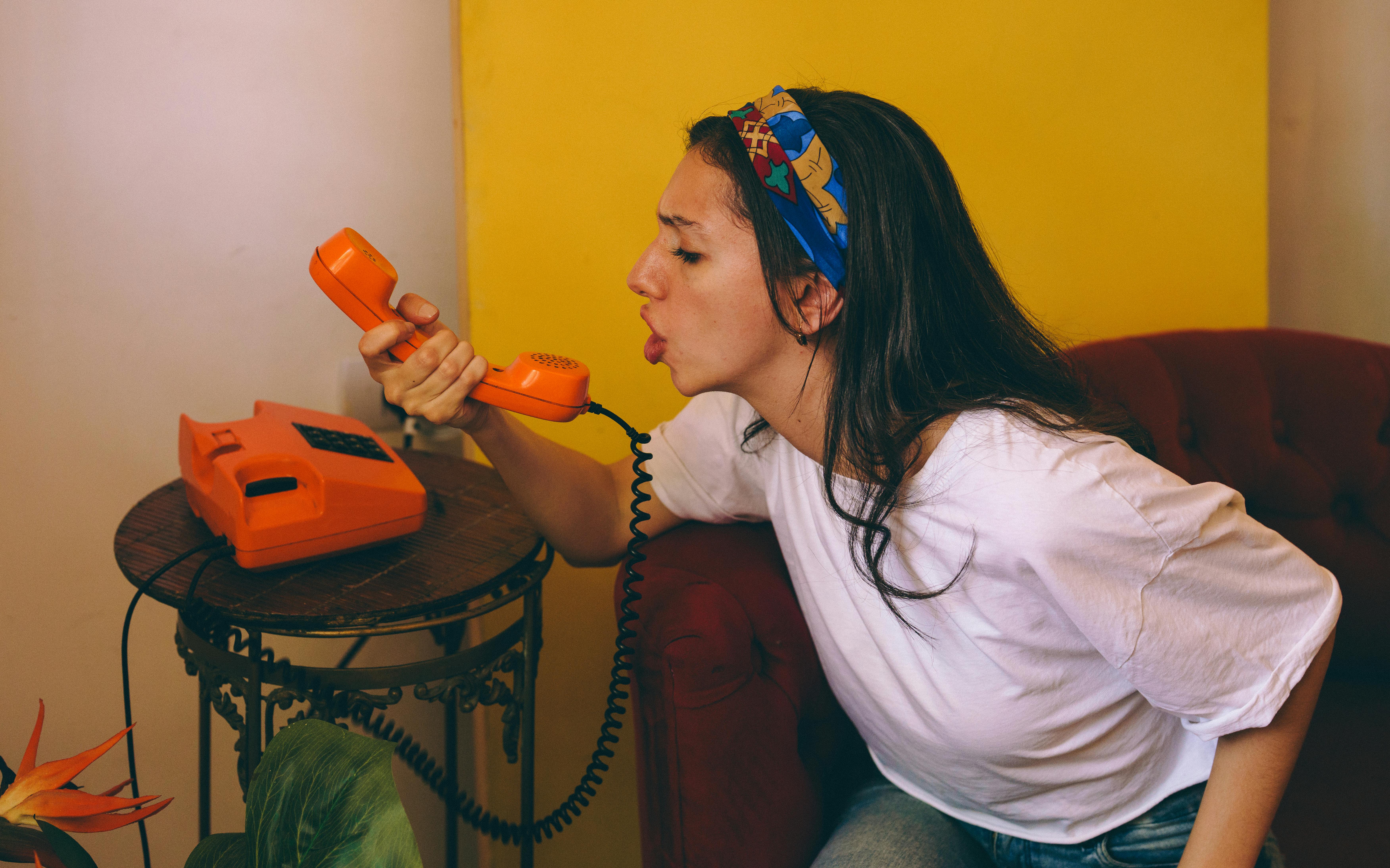 Kostenlos Junge Frau Benutzt Ein Altes Orangefarbenes Wählscheibentelefon Stock-Foto