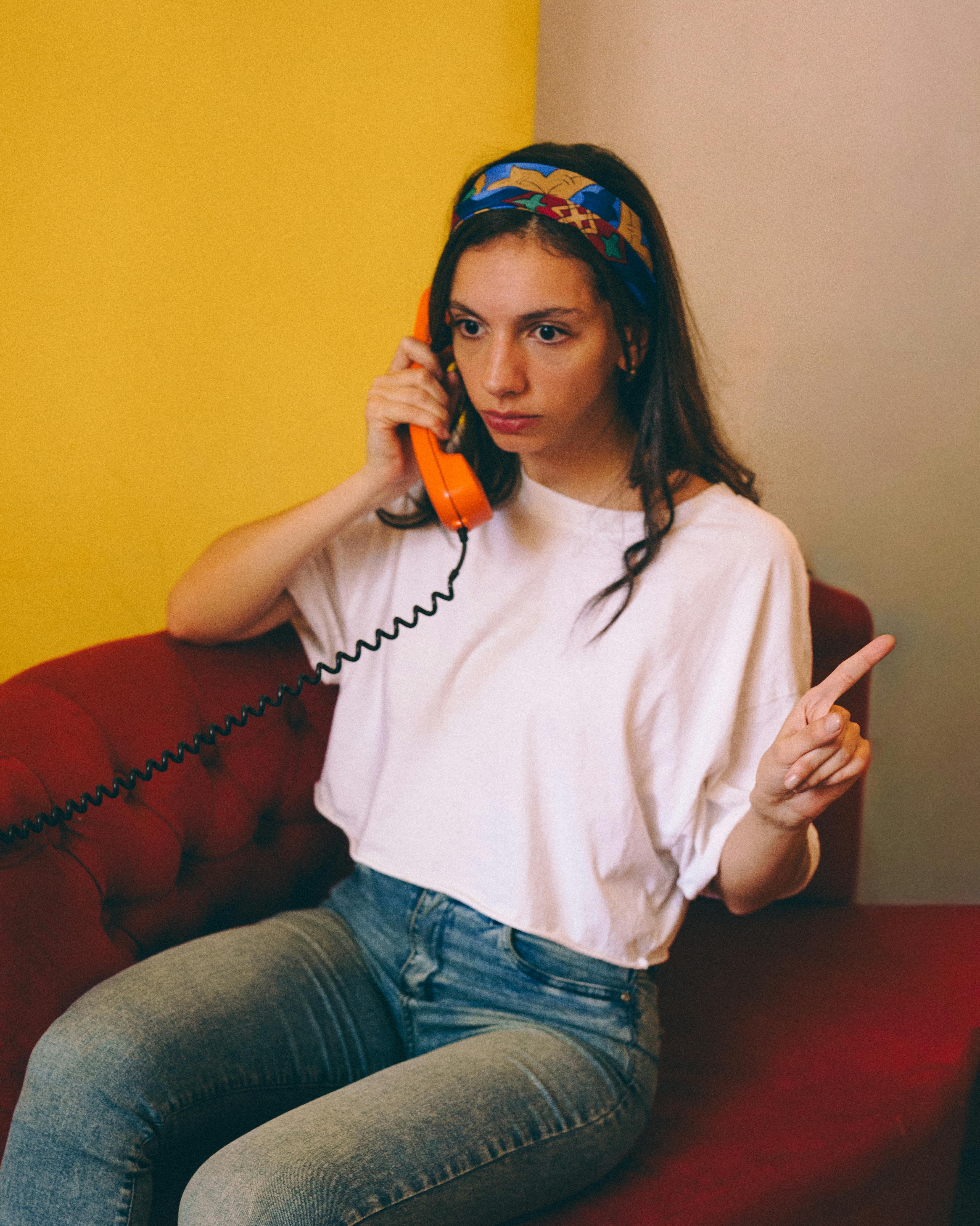 Ücretsiz Turuncu Sabit Hat Telefonunda Konuşan Genç Kadın Stok Fotoğraflar