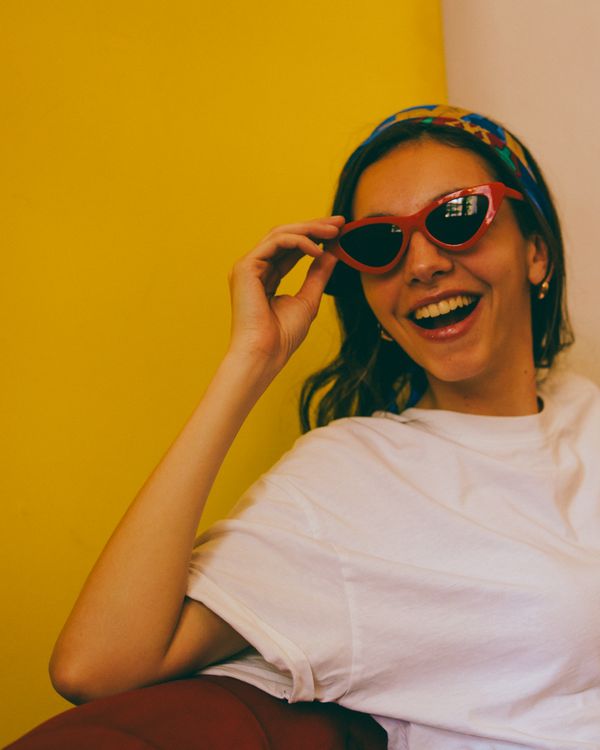 Laughing traveller in red sunglasses against a yellow wall — photo by Guillermo Berlin on Pexels
