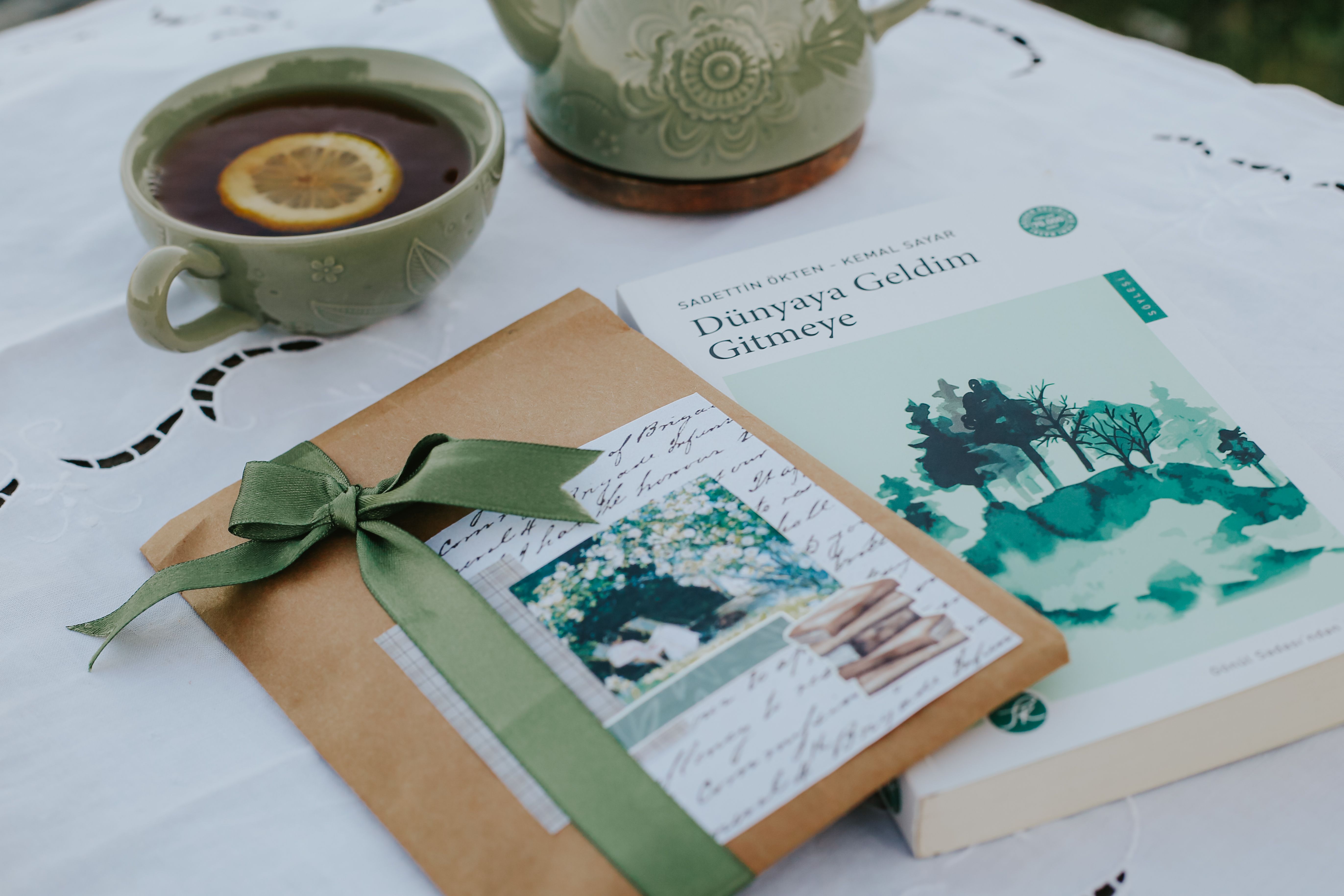 Charming still life of tea, book, and wrapped gift on a white tablecloth, evoking a cozy afternoon.
