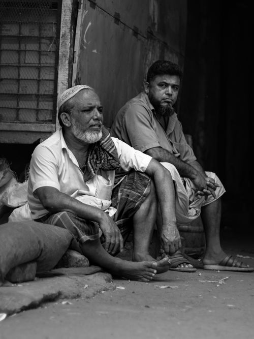 Free Two men sitting on a street display a thoughtful and contemplative demeanor in this black and white photograph. Stock Photo
