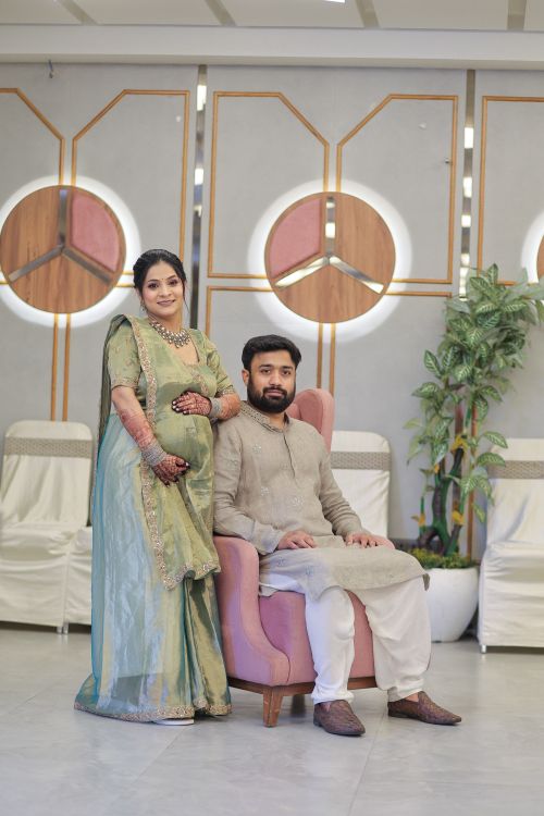 Free Couple in traditional attire during a maternity photoshoot indoors. Stock Photo