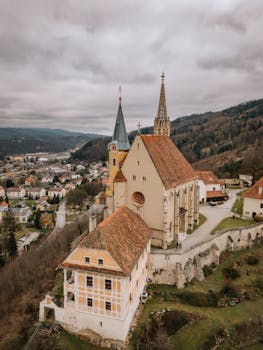 Discover the charm of a medieval church with a stunning aerial view of a European town.