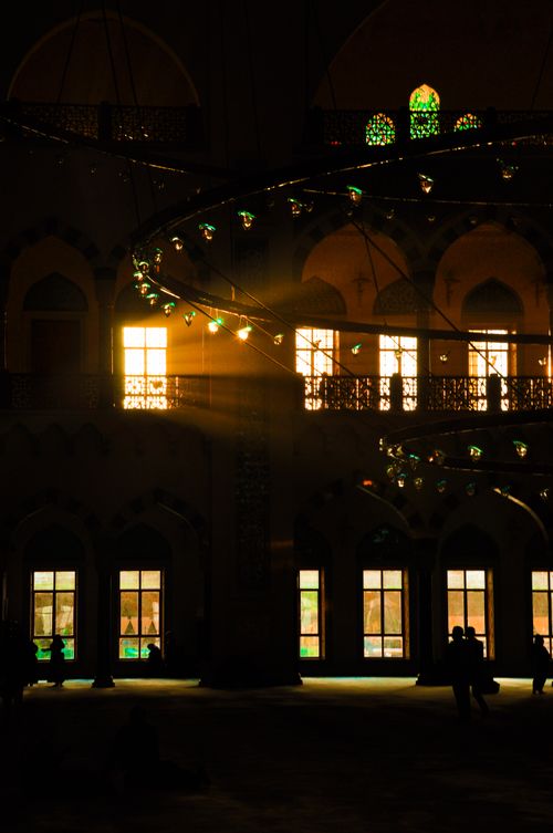 Free Sunlight streams through ornate windows casting a warm glow inside a grand mosque. Stock Photo