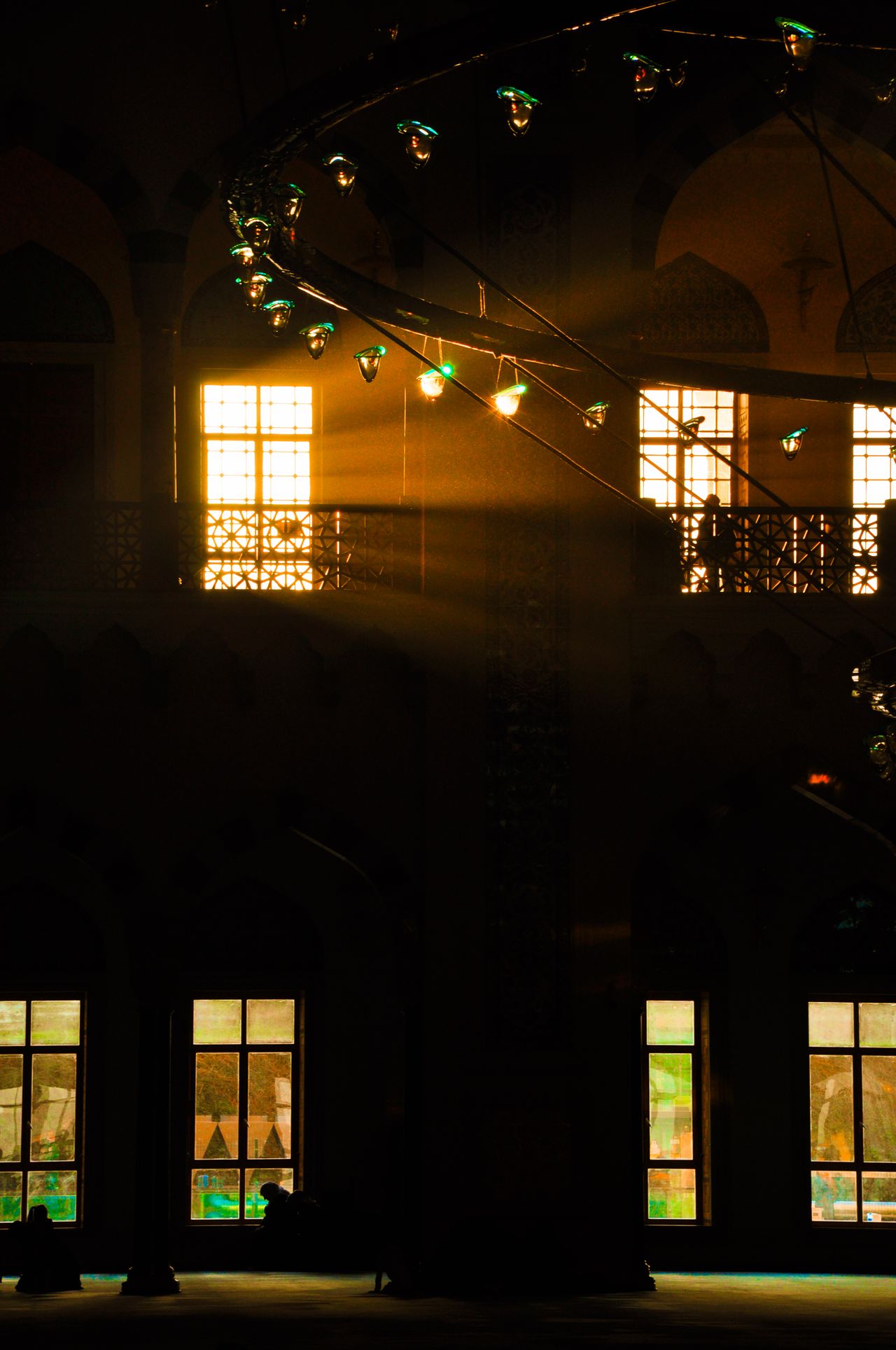 Sunlight streams into a historic mosque, illuminating its ornate architecture and stained glass windows