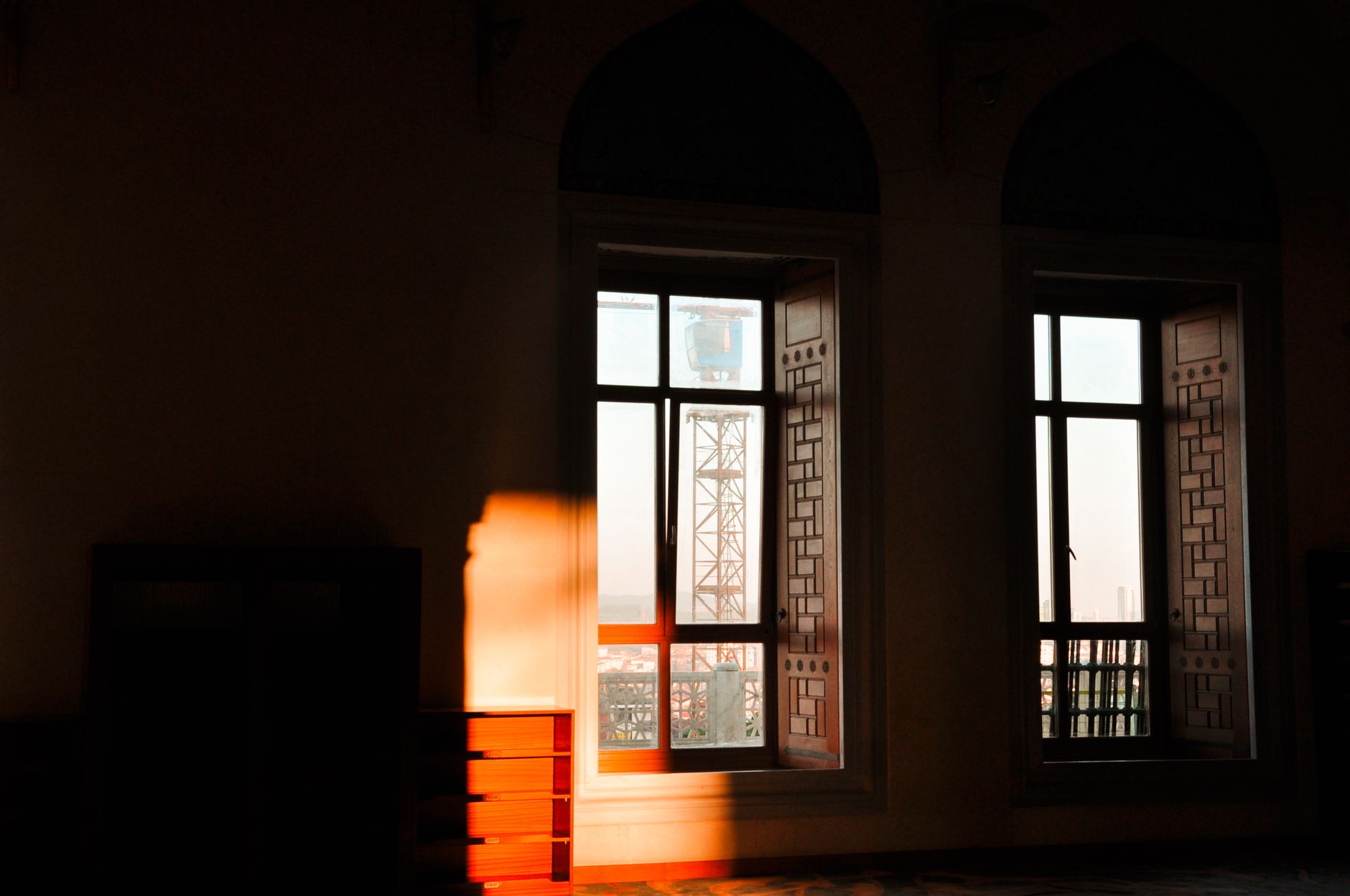 A room bathed in warm sunlight with decorative windows, featuring a city view through the glass.