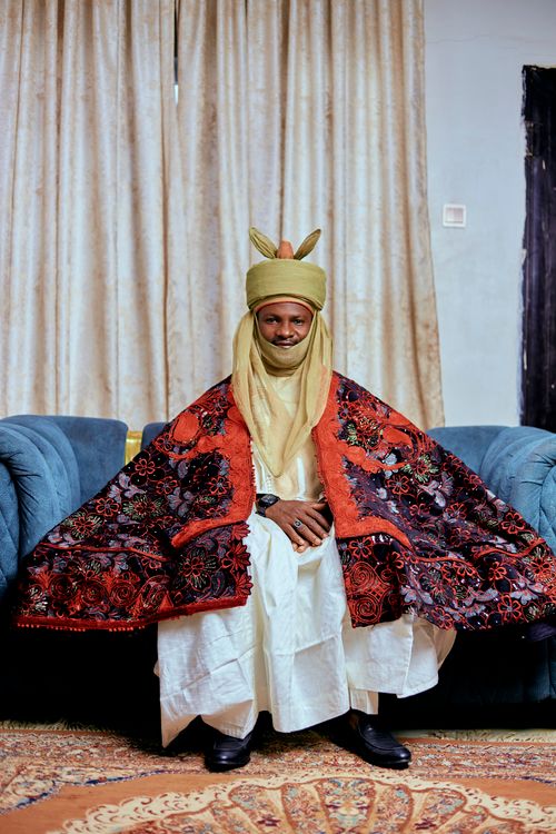 Free A person in vibrant traditional attire sits indoors on a sofa, exuding cultural elegance. Stock Photo