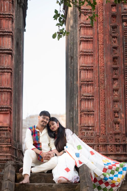 Free South Asian couple sitting in front of ornate temple gate in Ausgram, India, embracing culture and love. Stock Photo