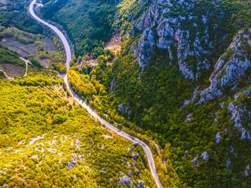 Free A stunning aerial view of a winding road cutting through lush green mountains, highlighting natural beauty. Stock Photo