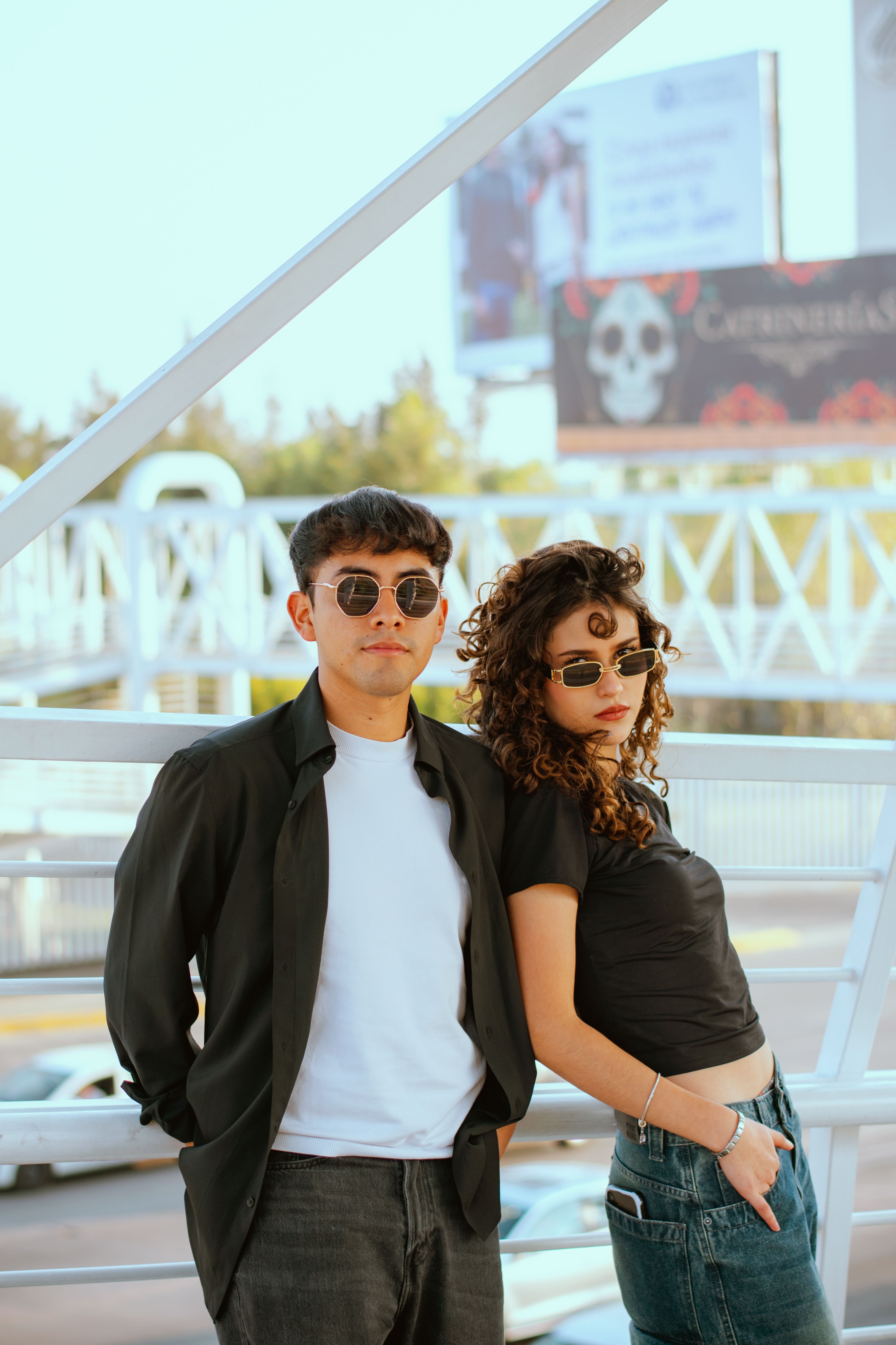 Stylish young couple wearing sunglasses posing outdoors on a sunny day.