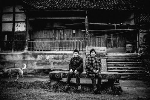 Grayscale Photo of Two People Sitting on Bench