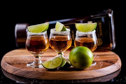 Free Close-up of three tequila shots on a wooden board with lime wedges and salt, perfect for cocktail moments. Stock Photo