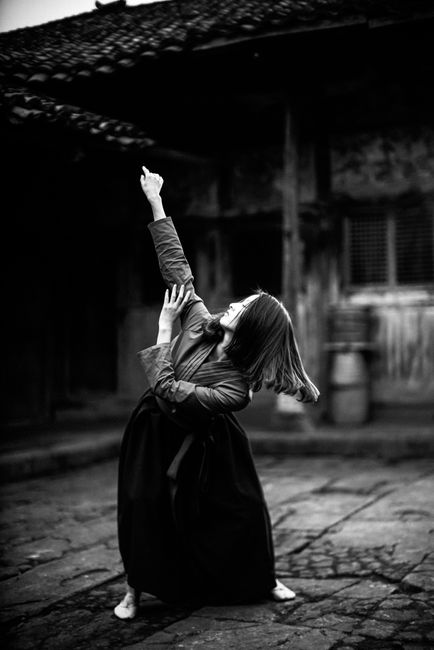 Artistic black and white photo of a woman dancing outdoors in vintage style.