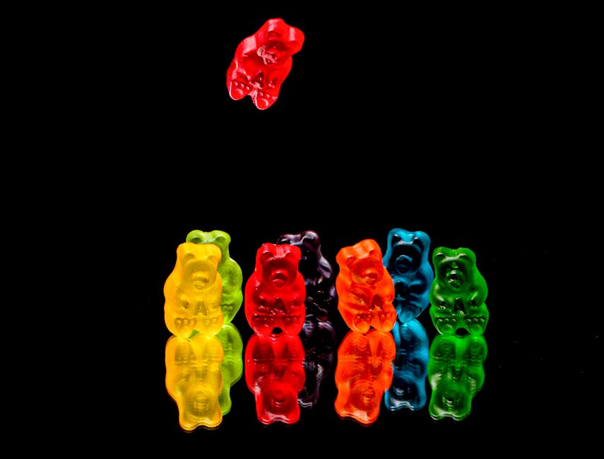 Vibrant gummy bears arranged on a reflective black surface.