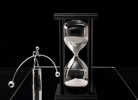 Black and white image of an hourglass with a balancing sculpture representing time and equilibrium.