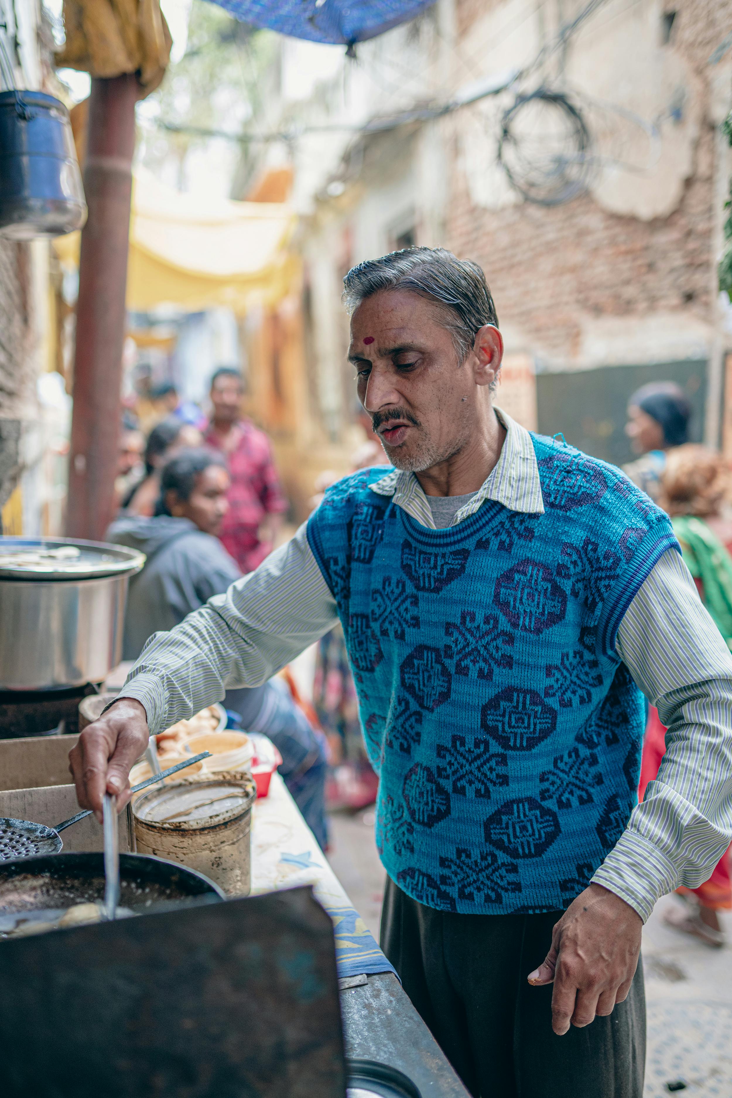 A street vendor prepares food in a bustling Varanasi alley, capturing local culture and daily life.