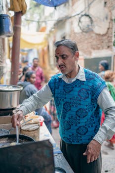 A street vendor prepares food in a bustling Varanasi alley, capturing local culture and daily life.