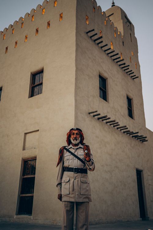 Free A traditional dressed guard stands in front of a historic fort in Abu Dhabi, UAE. Stock Photo