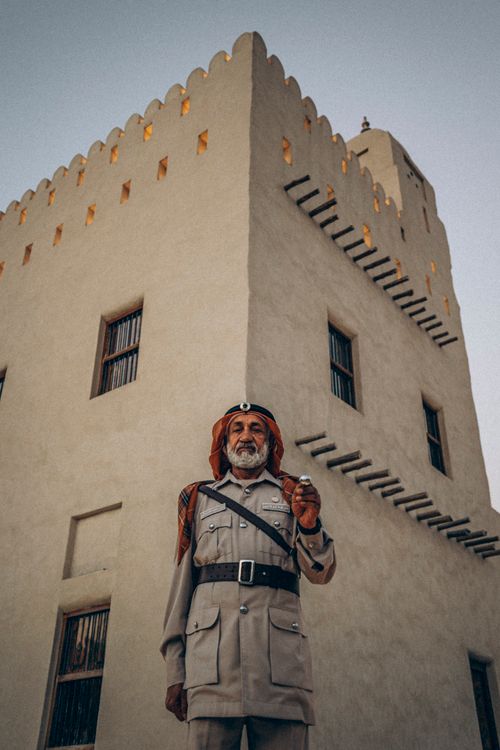 Free A traditional Emirati guard in uniform poses in front of a historic fort in Abu Dhabi. Stock Photo
