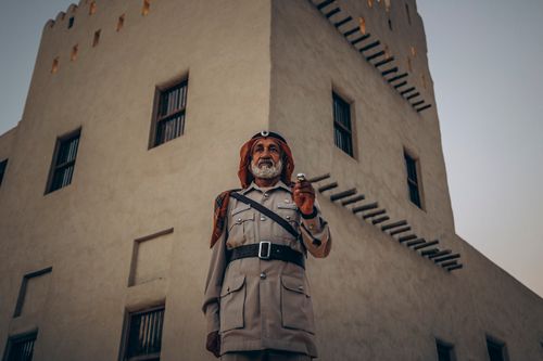 Free Portrait of a traditional Emirati police officer in front of a historic building in Abu Dhabi, UAE. Stock Photo